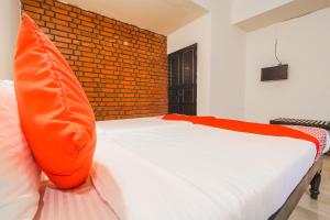 Schlafzimmer mit einem Bett mit orangefarbenem Kissen in der Unterkunft OYO La Petite Near Dabolim Airport in Chicolna