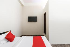 a room with a bed with a red pillow and a tv at OYO Samrat Residency in Faridabad