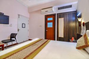 a bedroom with a bed and a door and a chair at Merit Hotel in Tājganj