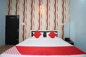 a bedroom with a bed with red pillows on it at Super Capital O Hotel Paradise Residency in Rāmnagar