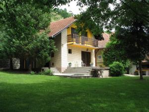 a yellow house with a balcony and a yard at Kuća Dragović in Voljevci
