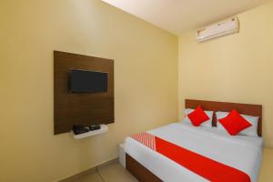 a bedroom with a bed with red pillows and a tv at OYO Jk Inn in Narasimharaja Puram
