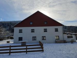 a large white building with a red roof in the snow at appart Hérisson RDC accessible PMR in Cornimont