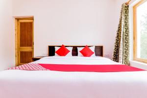 - une chambre avec un lit blanc et des oreillers rouges dans l'établissement OYO Deluxe United Corporate Home, à Airoli