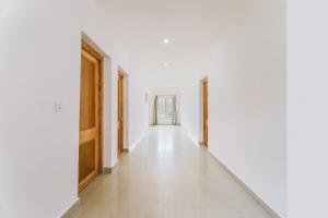 un couloir vide avec des murs blancs et des portes en bois dans l'établissement OYO Deluxe United Corporate Home, à Airoli