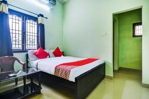 PodanūrにあるAruthraa Residencyのベッドルーム1室(赤い枕とテーブル付きのベッド1台付)