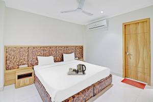 a bedroom with a large white bed and a wooden door at OYO Townhouse 691 Hotel Sulit in Tājganj
