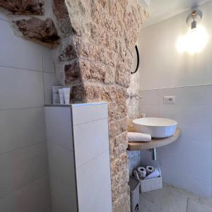 a bathroom with a sink and a stone wall at Trullo in Light in Alberobello