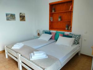 two twin beds in a room with a book shelf at Papas Rooms on the Seafront in Oreoí