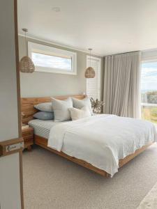 una camera da letto con un letto grande con lenzuola e cuscini bianchi di Travellers Rest Bicheno a Bicheno