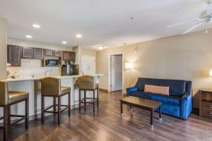 a living room with a blue couch and a kitchen at MainStay Suites Columbus next to Fort Moore in Columbus