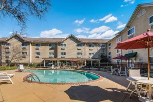 um grande edifício de apartamentos com piscina, mesas e cadeiras em MainStay Suites Columbus next to Fort Moore em Columbus