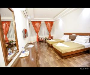 Habitación de hotel con 2 camas y espejo en Hotel Trupti International HUBLI, en Hubli