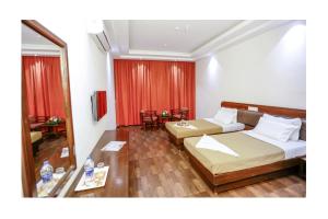 una camera d'albergo con due letti e uno specchio di Hotel Trupti International HUBLI a Hubli