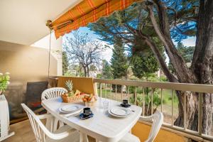 einen weißen Tisch und Stühle auf einem Balkon mit einem Baum in der Unterkunft Spacious apartment at a 5 min walk from the beach in Antibes