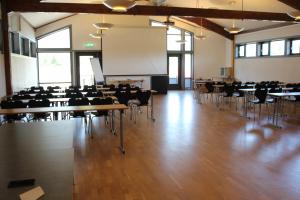 uma grande sala com mesas e cadeiras e uma tela de projeção em Heimat Brokelandsheia em Gjerstad