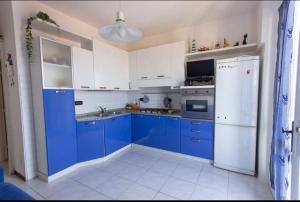 Una cocina con gabinetes azules y un refrigerador blanco. en Bilocale con ampio terrazzo, en Marciana Marina