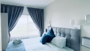 a bedroom with a bed with blue pillows and a window at Csig Vleesbaai in Vleesbaai