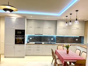 a kitchen with white cabinets and a table and chairs at Queen Isabella Premium in Vlorë