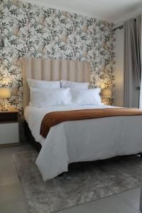 ein Schlafzimmer mit einem großen weißen Bett mit Blumentapete in der Unterkunft Nid de Rêve Accommodation in Midrand