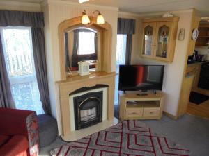 a living room with a fireplace and a television at 10 Berth on Coastfields with free WiFi Status in Ingoldmells