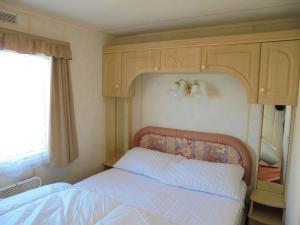 a bedroom with a bed with a wooden headboard at 10 Berth on Coastfields with free WiFi Status in Ingoldmells