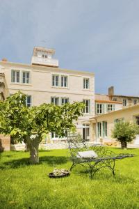 a park bench sitting in the grass in front of a building at LE LANTERNON in Saint-Martin-de-Ré