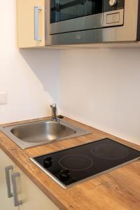 eine Küchentheke mit einer Spüle und einer Mikrowelle in der Unterkunft Family&Friends Apartments Schönbrunn in Wien