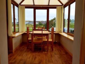 a dining room with a table and chairs and windows at OneRavensLane in Stornoway
