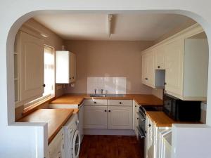 una cocina con armarios blancos y encimeras de madera en OneRavensLane en Stornoway
