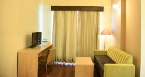 Habitación de hotel con sofá, escritorio y TV en Starlit Suites Shirdi, en Nighoj