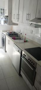 a white kitchen with a sink and a stove at Blue Largo Sea View in Westbrook