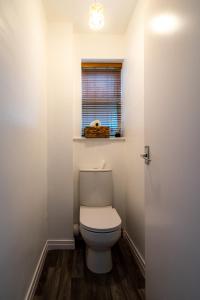 a bathroom with a toilet with a window and a door at Jane & Julies place in Gresford