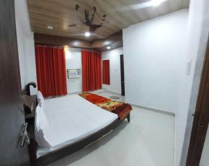 um pequeno quarto com uma cama e cortinas vermelhas em OYO Rajeswari Continental em Kanpur