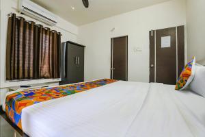 ナーグプルにあるFabHotel Elite Palmのベッドルーム(カラフルな毛布付きの大きな白いベッド付)