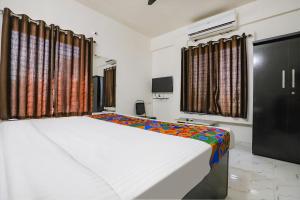 a bedroom with a large white bed and windows at FabHotel Elite Palm in Nagpur