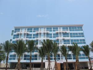 a tall building with palm trees in front of it at Nantra Pattaya Baan Ampoe Beach in Na Jomtien