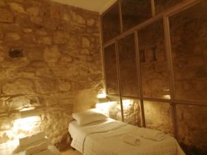 1 dormitorio con cama y pared de piedra en Dana Gardens Hotel en Ḑānā