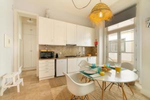 a kitchen with a table and white cabinets and a table and chairs at Alcácer Flat in Alcácer do Sal