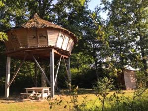 a tree house with a picnic table in a field at Domaine de la Puisaye in Grandchamp