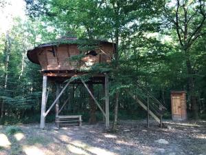 a tree house with a bench in the woods at Domaine de la Puisaye in Grandchamp
