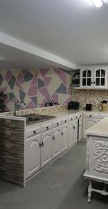 a kitchen with white cabinets and a geometric wall at La maison du bonheur in Celavisa