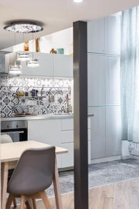 a kitchen with white cabinets and a table and a chair at Venus Apartments - City Park II in Budapest