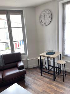 a living room with a couch and a table and a clock at Studio atypique centre Vivonne in Vivonne