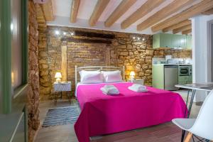 a bedroom with a pink bed and a kitchen at Venetian Sterna Casa in Corfu Town