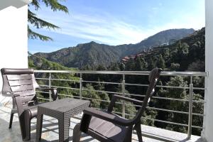 two chairs and a table on a balcony with mountains at Dhanolti View By LA Riqueza - Centrally Located - Lift & Parking Facility in Dhanaulti