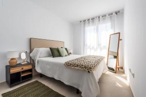 biała sypialnia z łóżkiem i lustrem w obiekcie Apartamento Dora Maar I w Marbelli
