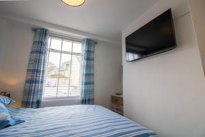 a bedroom with a bed and a flat screen tv at Saltwhistle Beach- Couples Retreat in Teignmouth