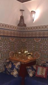 Cette chambre dispose d'un canapé et d'une table avec une croix sur le mur. dans l'établissement Mini Riad family Chez Adil Batha Fés, à Fès 45 autres photos
