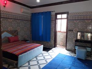 une chambre avec un lit et un rideau bleu dans l'établissement Mini Riad family Chez Adil Batha Fés, à Fès